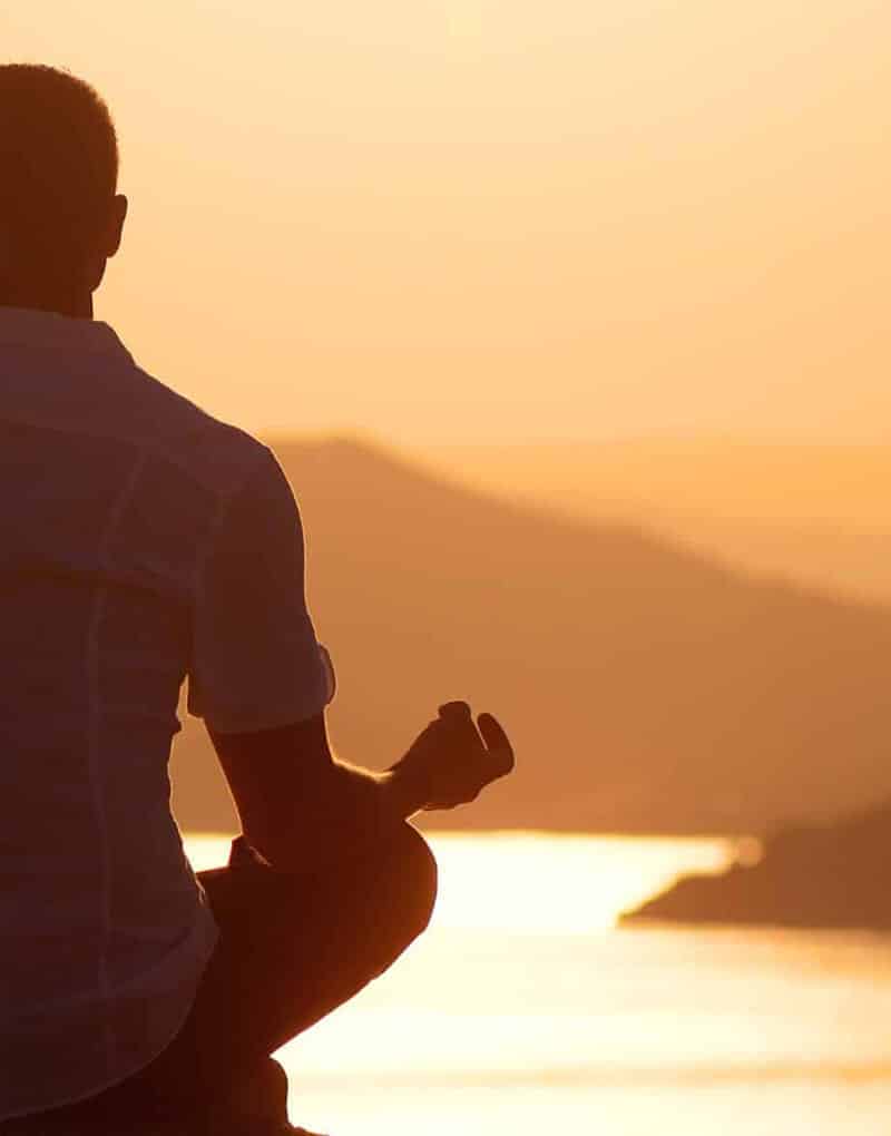 man meditating at sunset